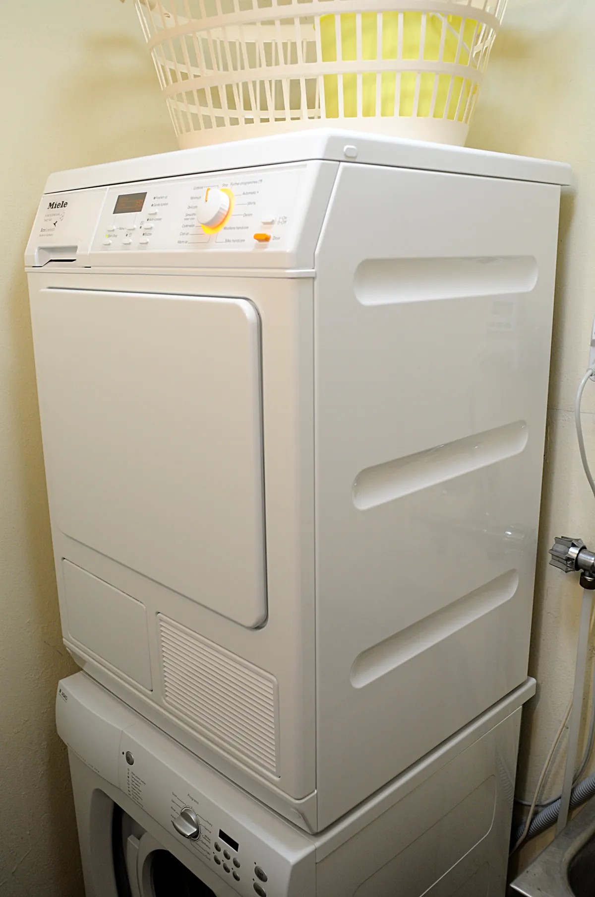 Dryer stacked on a washer in a laundry nook with a basket on top