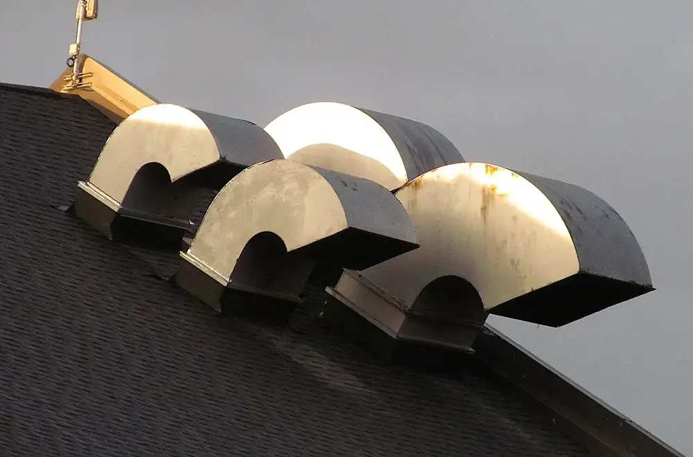 Four metal hooded vent caps on a shingled roof